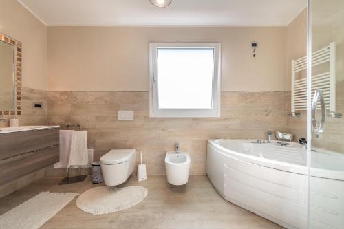 a bathroom with a tub and a toilet and a sink at Villa Maria Beatrice in Quartu SantʼElena