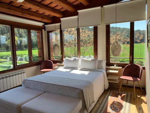 um quarto com uma cama com 2 cadeiras e janelas em Hotel Masia La Palma em Espinavesa