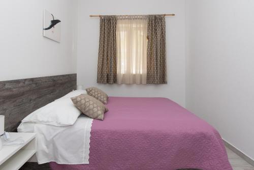 a bedroom with a bed with a purple blanket at Apartments Lovrić in Vodice