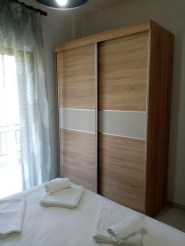 a large wooden cabinet with two towels on a bed at Deaspoina Apartments in Nea Roda