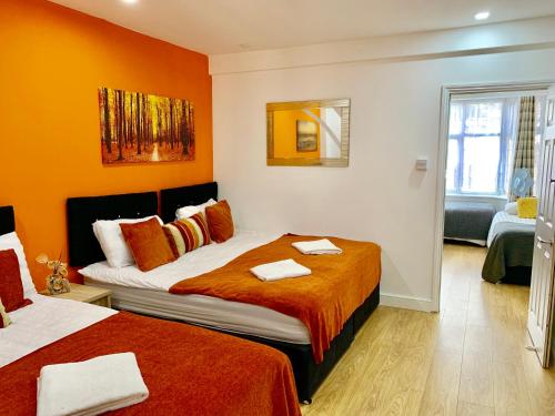um quarto com 2 camas e paredes cor-de-laranja em London Luxury 2Bedrooms, Reception, Garden, Apartment em Ilford
