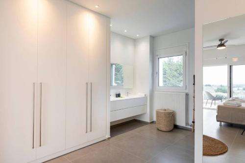 a white bathroom with a sink and a mirror at Melia Villa Kos with Heated Pool in Kos Town