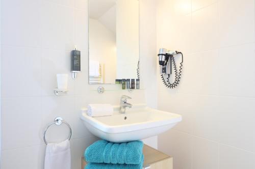 a white bathroom with a sink and a mirror at Trinite Hotel in La Trinité-sur-Mer