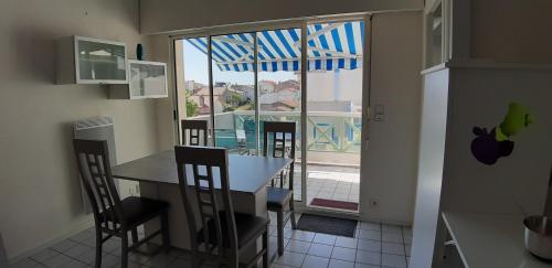 une cuisine avec une table et des chaises ainsi qu'une grande fenêtre dans l'établissement Appart 6 personnes, 3 min à pied de la plage et du centre ville, à Saint-Georges-de-Didonne
