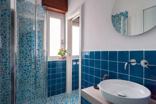 La salle de bains est pourvue de carrelage bleu, d'un lavabo et d'une douche. dans l'établissement President Suite, à Salerne