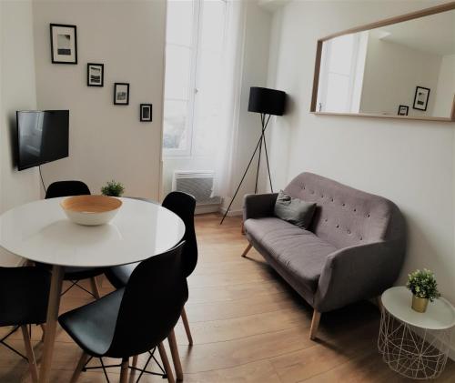 a living room with a couch and a table at L'Authentique - Situé en face des thermes et tout proche du coeur de ville in Rochefort