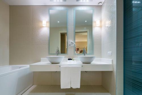 uma casa de banho com 2 lavatórios, um espelho e uma banheira em Base Hotel em Noventa di Piave