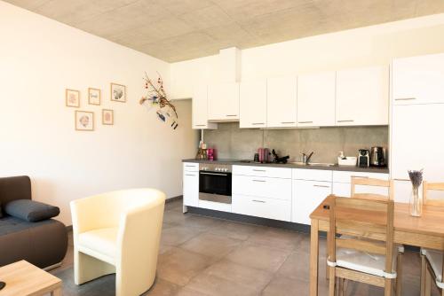 a kitchen with white cabinets and a wooden table at L'appartement in Reconvilier