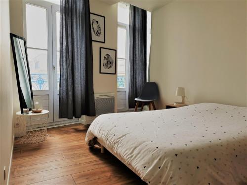 a bedroom with a bed and two windows at ROCHEFORT authentique in Rochefort