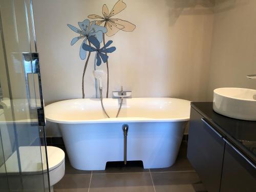 ein Badezimmer mit einer Badewanne mit einer Blume an der Wand in der Unterkunft Alcazaba Beach Luxury Apartment02 Estepona in Estepona