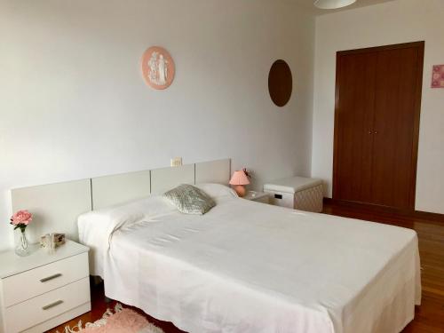 a bedroom with a white bed and a wooden floor at Apartamento Playa de Carnota in Carnota