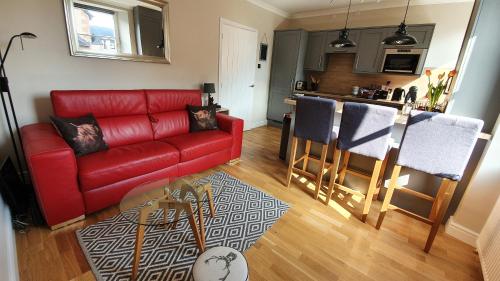 a living room with a red couch and a kitchen at Smart & Cozy Holiday Apartment in the city centre in Inverness