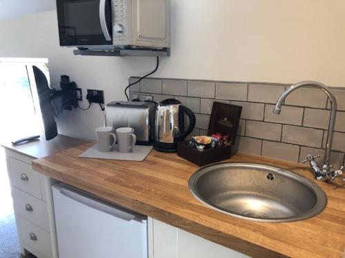 a kitchen counter with a sink and a microwave at Christmas Hill Farm in Gaydon