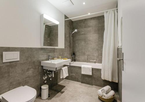 a bathroom with a toilet and a sink and a tub at Swiss Star Home in Effretikon