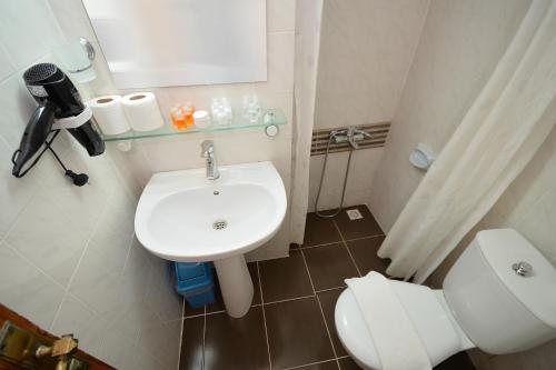 a bathroom with a white sink and a toilet at Kerman Hotel in Çeşme