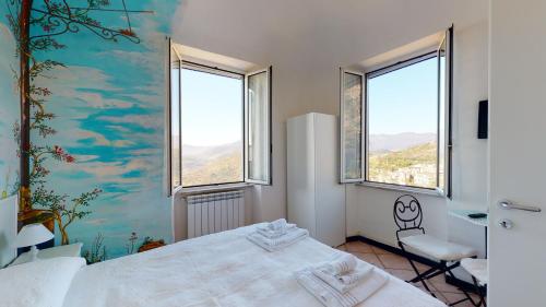een slaapkamer met een wit bed en 2 ramen bij B&B La Canonica - Svegliarsi a Verezzi in Borgio Verezzi