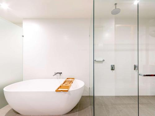 a white bath tub sitting next to a white toilet at Novotel Brisbane South Bank in Brisbane
