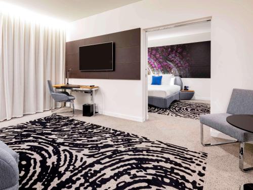 a hotel room with a couch and a bed and a television at Novotel Brisbane South Bank in Brisbane