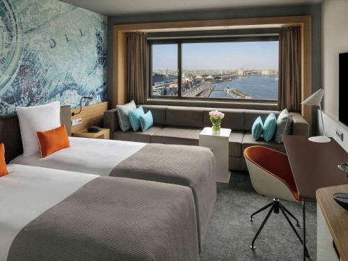 una camera d'albergo con due letti, una scrivania e una finestra di Mövenpick Hotel Amsterdam City Centre ad Amsterdam