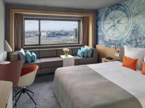 a hotel room with a bed and a couch and a window at Mövenpick Hotel Amsterdam City Centre in Amsterdam