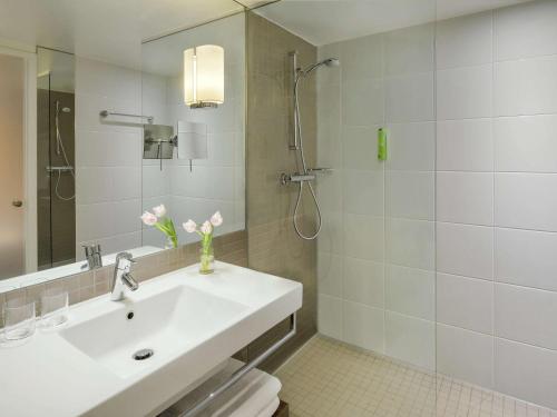 une salle de bain blanche avec un lavabo et une douche dans l'établissement Mövenpick Hotel Amsterdam City Centre, à Amsterdam