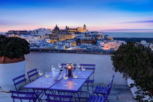 a table with wine glasses and a view of a city at Bartago Luxury House in Ostuni