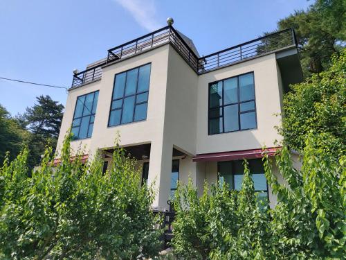 a large white house with black windows at Rooftop Moonlight Pension in Gangneung