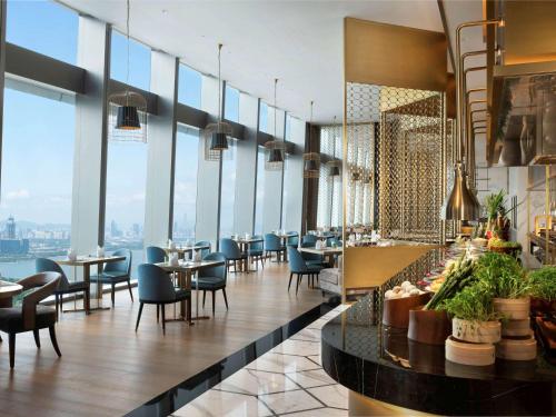 a restaurant with tables and chairs and windows at Raffles Shenzhen, Situated in the heart of One Shenzhen Bay, Book Now to Enjoy Free Minibar and Happy Hour Privileges at Long Bar on 71F in Shenzhen