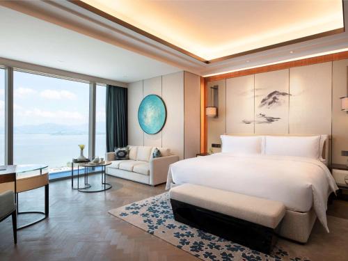 a bedroom with a large bed and a living room at Raffles Shenzhen, Situated in the heart of One Shenzhen Bay, Book Now to Enjoy Free Minibar and Happy Hour Privileges at Long Bar on 71F in Shenzhen