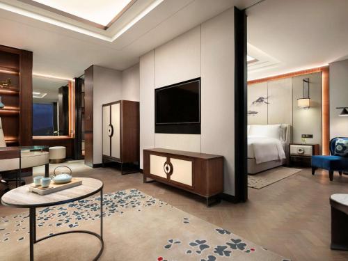 a hotel room with a bed and a television at Raffles Shenzhen, Situated in the heart of One Shenzhen Bay, Book Now to Enjoy Free Minibar and Happy Hour Privileges at Long Bar on 71F in Shenzhen
