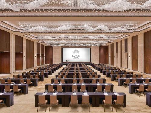 a large room with tables and chairs and a screen at Raffles Shenzhen, Situated in the heart of One Shenzhen Bay, Book Now to Enjoy Free Minibar and Happy Hour Privileges at Long Bar on 71F in Shenzhen