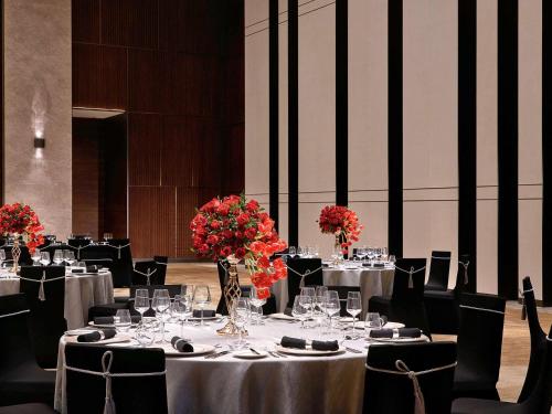 a dining room with tables and chairs with flowers on them at Raffles Shenzhen, Situated in the heart of One Shenzhen Bay, Book Now to Enjoy Free Minibar and Happy Hour Privileges at Long Bar on 71F in Shenzhen