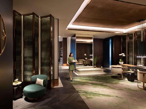 a person standing in a lobby with a room at Raffles Shenzhen, Situated in the heart of One Shenzhen Bay, Book Now to Enjoy Free Minibar and Happy Hour Privileges at Long Bar on 71F in Shenzhen