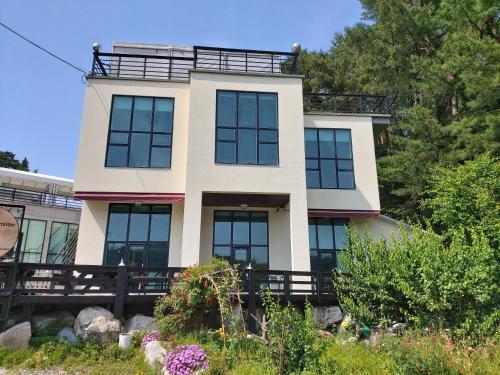 une maison avec un balcon au-dessus dans l'établissement Rooftop Moonlight Pension, à Gangneung