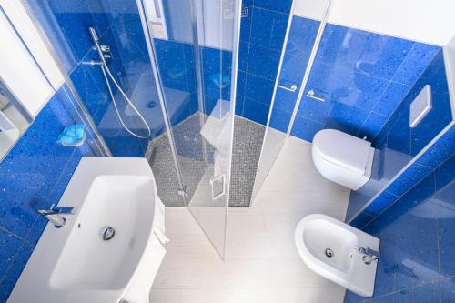 baño azul y blanco con aseo y lavamanos en Hotel Capri 3 Stelle SUPERIOR, en Lido di Jesolo