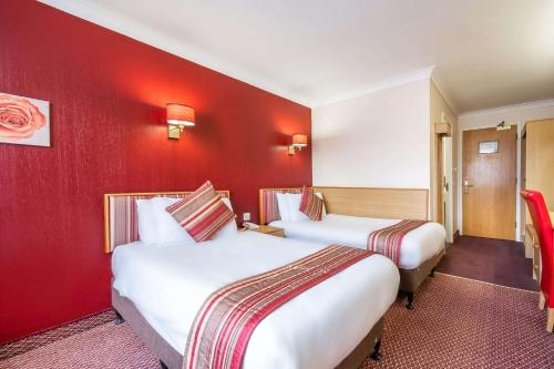 two beds in a hotel room with red walls at Comfort Inn Arundel in Arundel