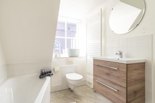 a bathroom with a toilet and a sink and a mirror at Herenweg Apartments in Hollum