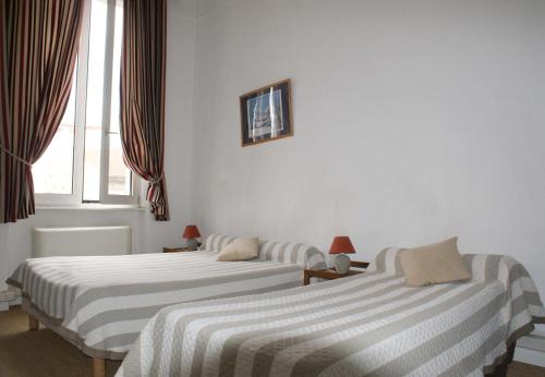 two beds in a room with white walls and a window at Hôtel Jaurès in Toulon