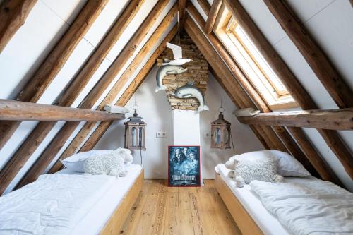 two beds in a attic room with wooden beams at Herenweg Apartments in Hollum