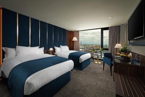 um quarto de hotel com duas camas e uma grande janela em The Savoy Hotel em Limerick