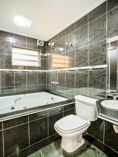 a bathroom with a tub and a toilet and a sink at Hotel Anália Franco in Sao Paulo