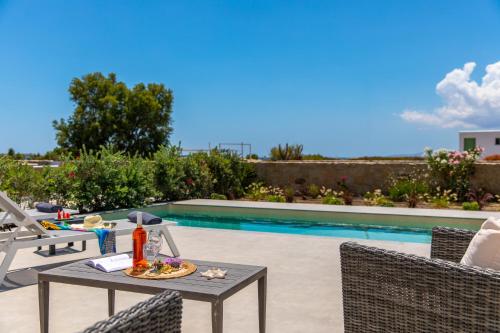 a patio with a table and chairs next to a swimming pool at Salinus Beachfront Private Pool Villas in Plaka