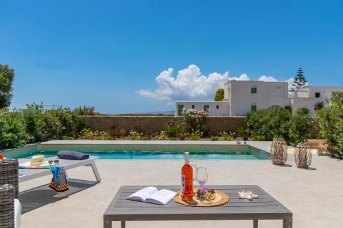 a table with a bottle of wine on it next to a pool at Salinus Villas in Plaka