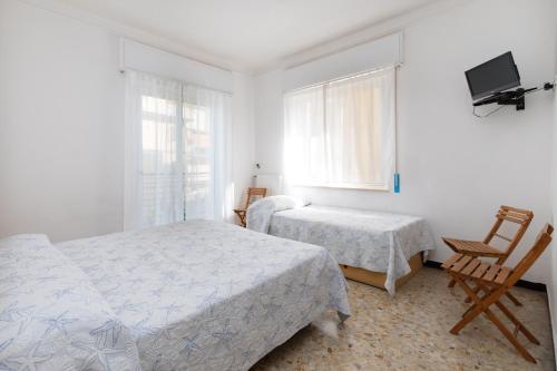 a bedroom with two beds and a tv and a chair at San Francisco rooms in Marina di Andora