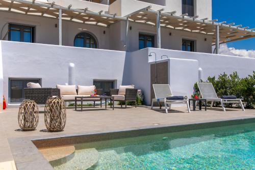 a patio with chairs and a pool in front of a building at Salinus Beachfront Private Pool Villas in Plaka