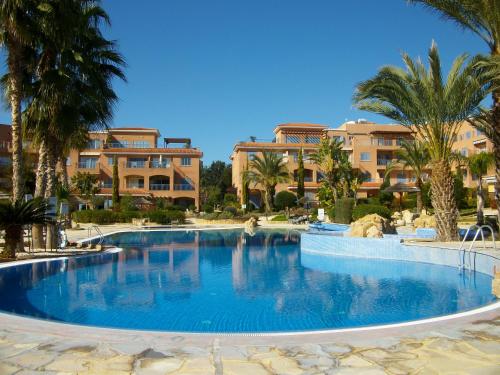 a large swimming pool with palm trees and buildings at Resitour - Limnaria Gardens in Paphos