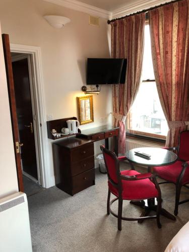 um quarto de hotel com uma secretária, uma mesa e cadeiras em Leeson Bridge Guesthouse em Dublin