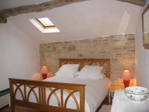 1 dormitorio con cama y pared de ladrillo en La Ferme de l'Eglise, en Vanzay