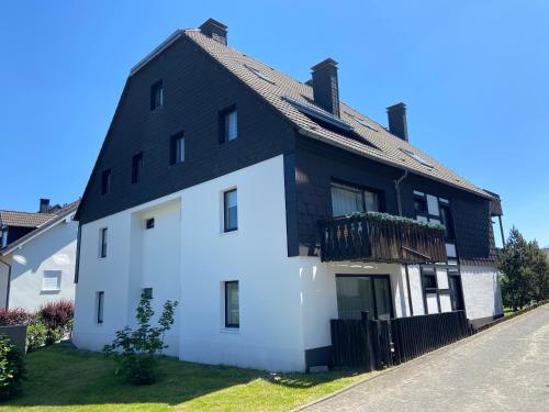 a white and black house with a black roof at Ferienwohnung Fichtenweg in Winterberg