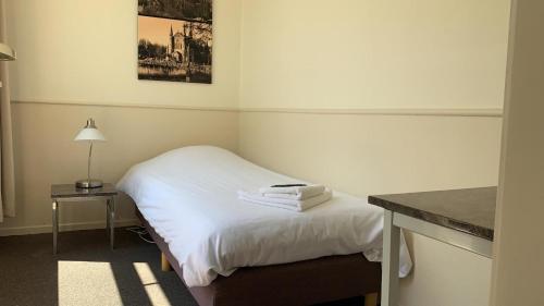 a hotel room with a bed and a table with a lamp at Hotel Stad en Land in Alkmaar